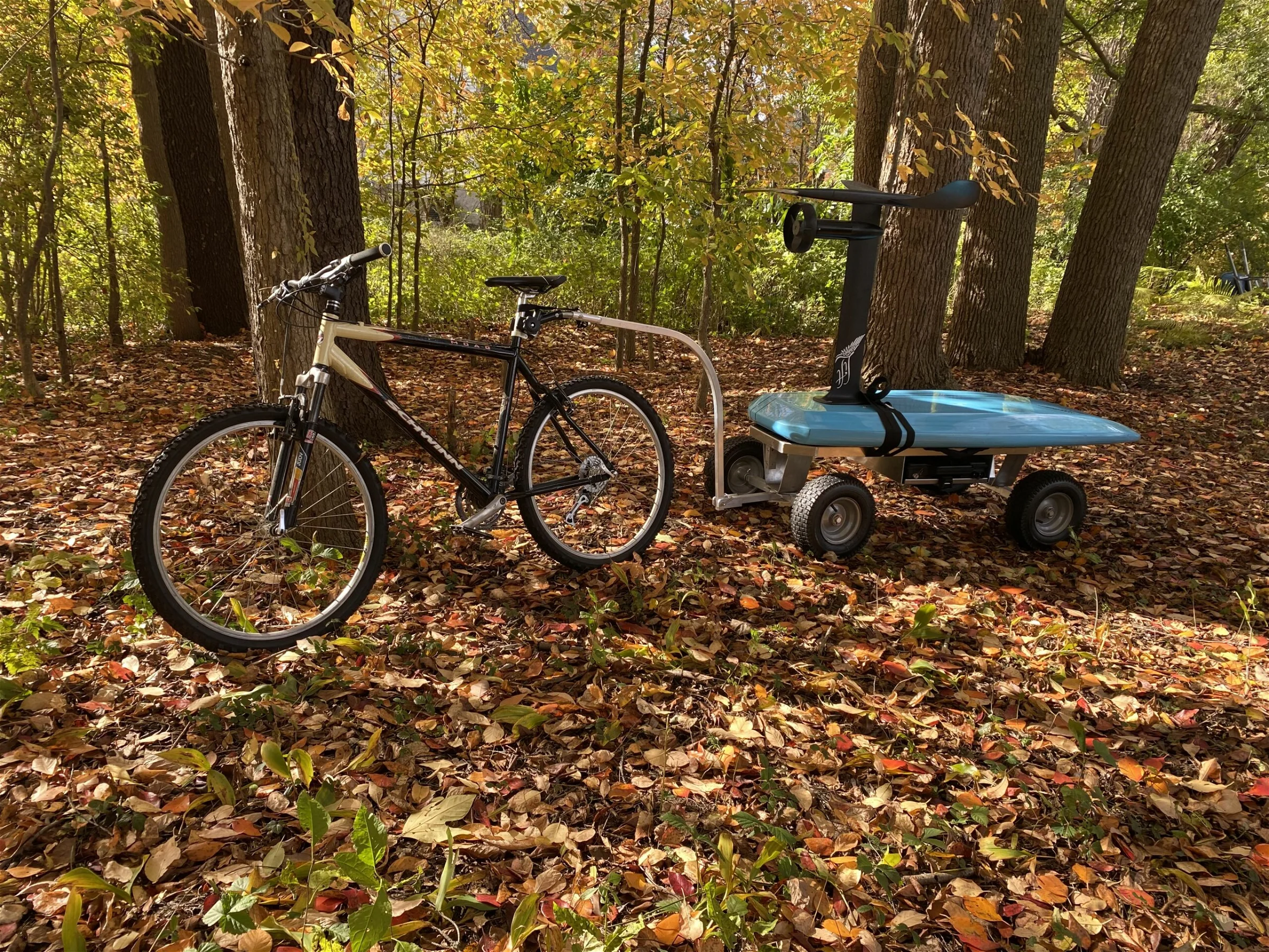 A bike with a wagon attached using the bike attachment accessory from Kahuna Wagons, in the woods surrounded by leaves.