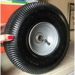 A person with red nails holding up a 10″ Pneumatic Tire showing the front.