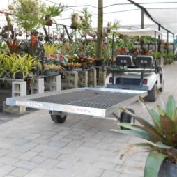 A SEMI-TRACKING TRAILER attached to a golf cart in a garden nursery center.