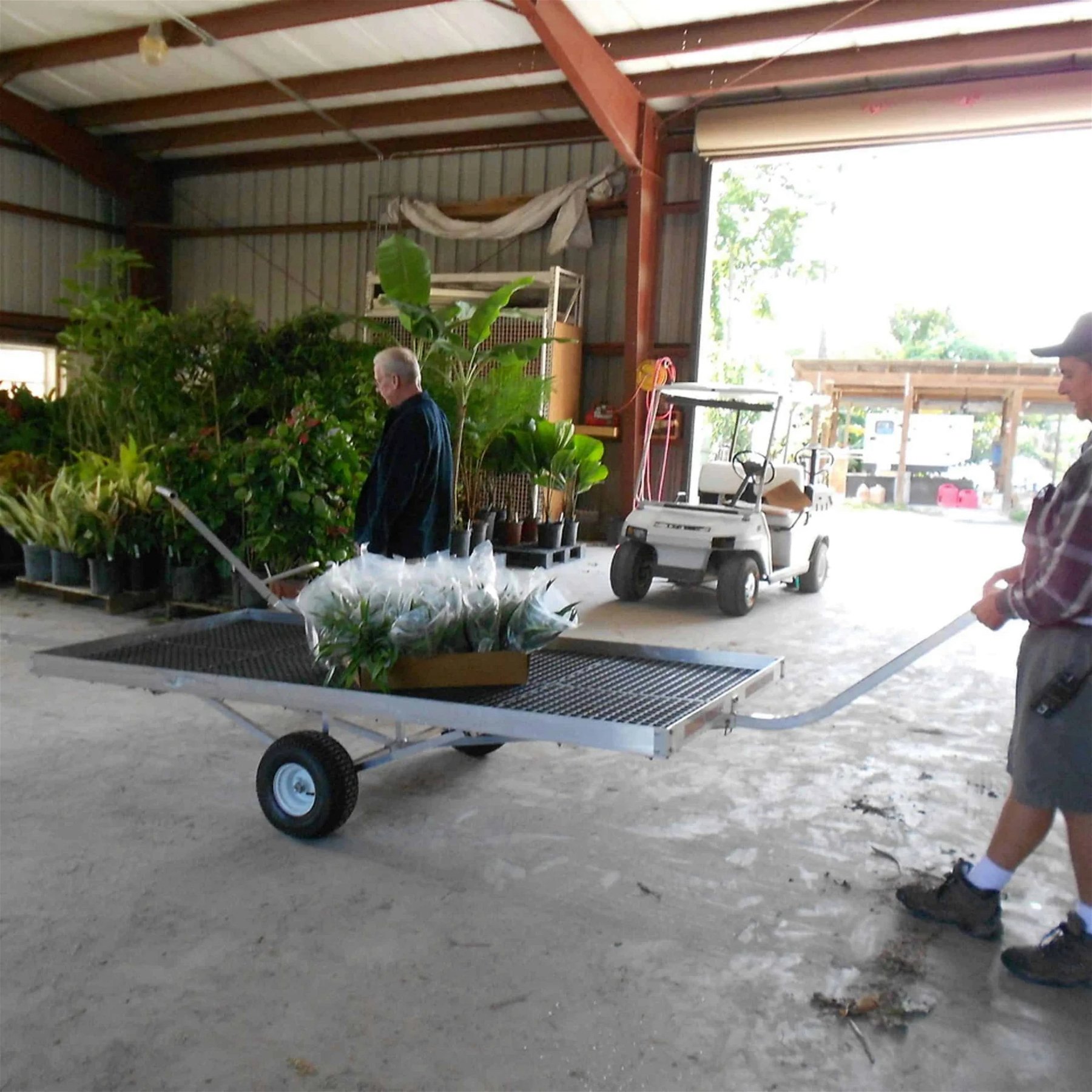 A person using the SEMI-TRACKING TRAILER with potted plants