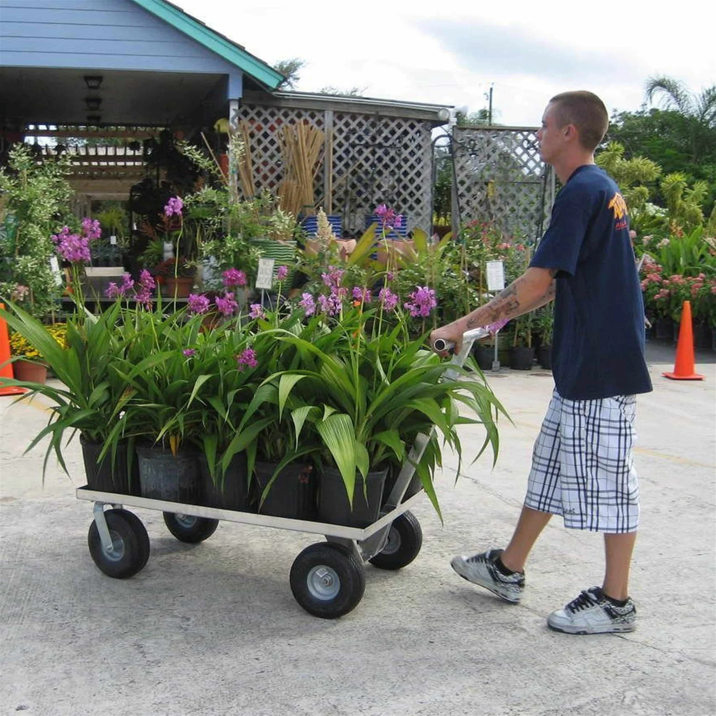 A person using the Kahuna Wagon all aluminum Push Wagon loaded with potted plants.