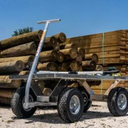 Kahuna wagon with all-terrain tires, placed n next to wooden logs and lumber piles.