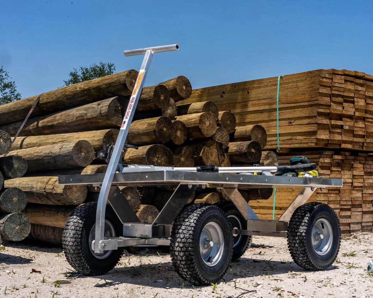 Kahuna wagon with all-terrain tires, placed n next to wooden logs and lumber piles.